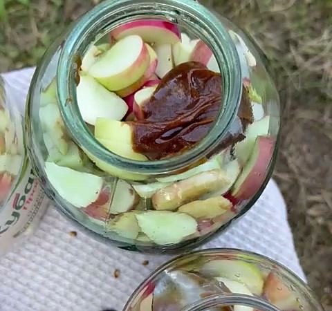 Ложка натурального мёда над банкой с яблоками